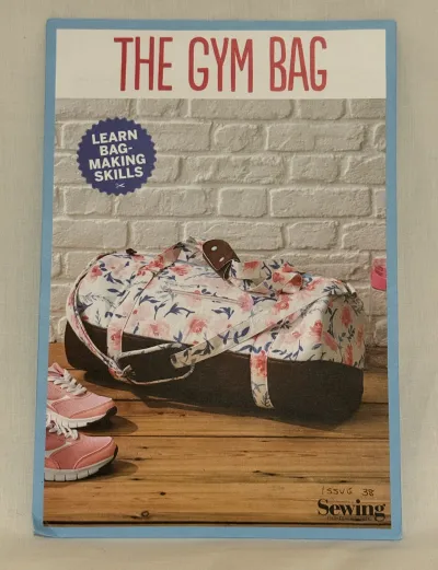 A gym bag sewing pattern by Simply Sewing. On the cover is a two tone gym bag sat next to a pair of trainers.