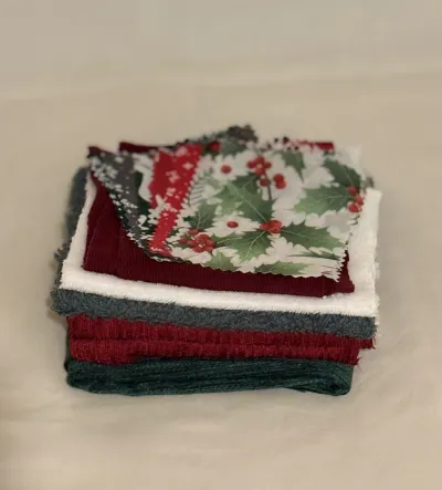 Multiple pieces of folded fabric, there is a mix of Christmas colours and patterns.