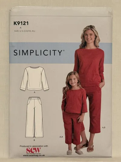 A Simplicity K9121 sewing pattern in sizes XS-XL and ages 3-8. On the cover are a mother and daughter wearing matching outfits, to one side is a drawing of a top and pair of trousers.